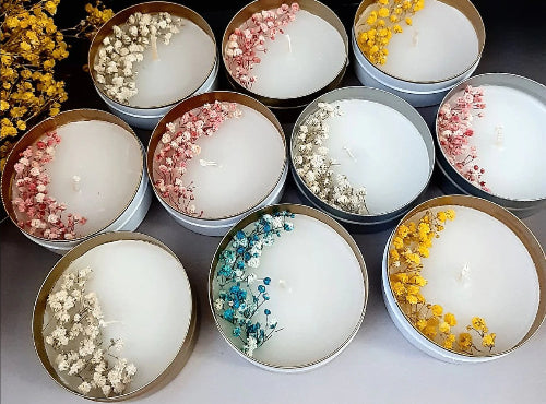 Assorted candles in tins with floral elements on a dark surface