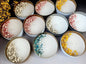 Assorted candles in tins with floral elements on a dark surface