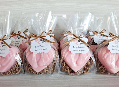 Pink heart-shaped treats in clear bags with brown ribbons and labels on a light gray background