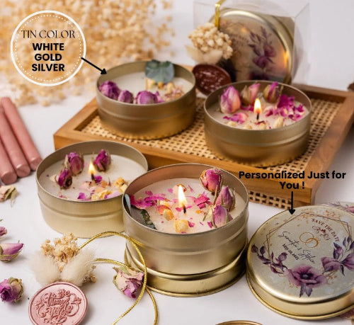 Decorative candles in gold tins with floral elements on a white surface.